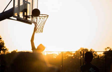 Ein Basketballspieler trifft einen Korb im Sonnenuntergang, symbolisch für das Erreichen von Zielen und einen erfolgreichen Start ins Jahr